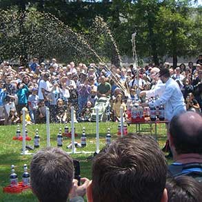 Tow men in lab coats squirt streams of foamy soda as a large crowd watches