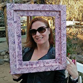 A woman holds a picture frame that frames her face